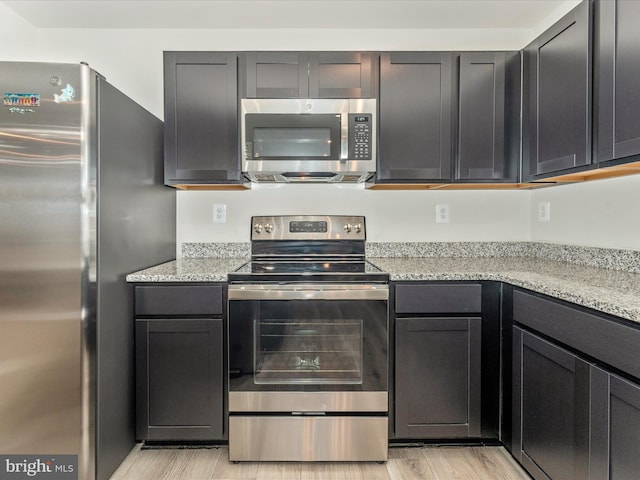 kitchen featuring light stone countertops, stainless steel appliances, and light hardwood / wood-style floors