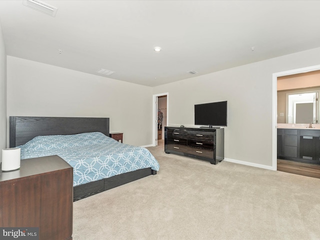 carpeted bedroom with a walk in closet, connected bathroom, a closet, and sink