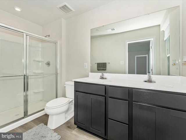 bathroom with hardwood / wood-style flooring, vanity, toilet, and an enclosed shower