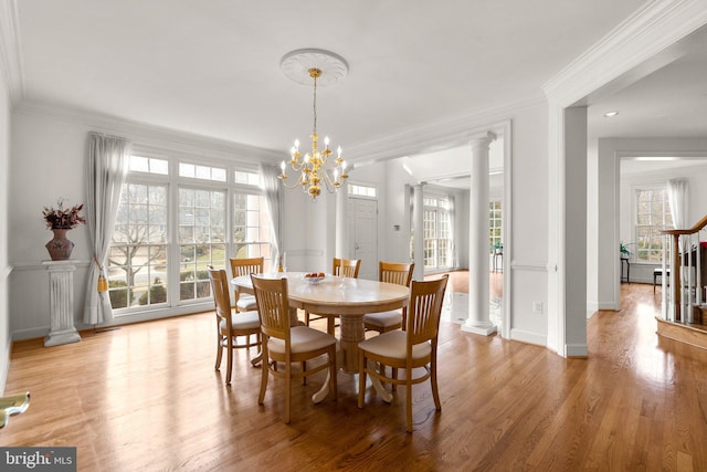 dining area with ornate columns, light wood-style flooring, and crown molding