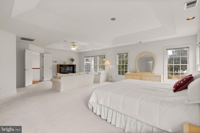 bedroom with carpet floors, visible vents, and a raised ceiling