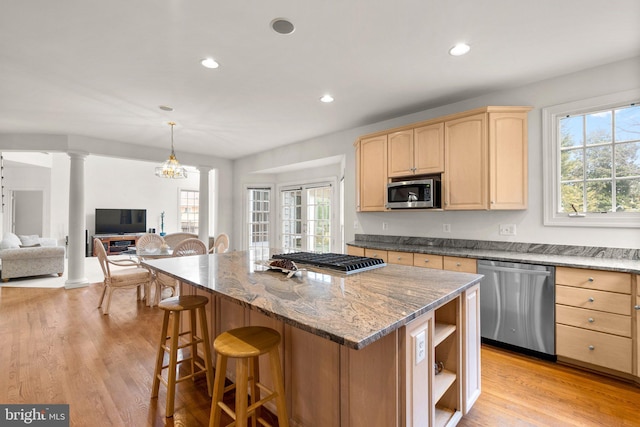 kitchen with stainless steel appliances, light brown cabinetry, a kitchen island, and ornate columns