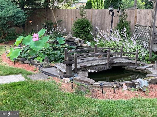 exterior details featuring fence and a garden pond