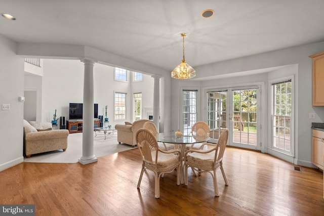 dining room with ornate columns, light wood-style flooring, a fireplace, and baseboards