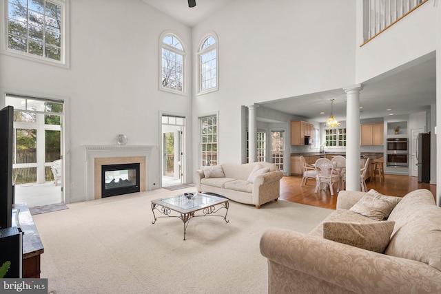 living room with wood finished floors, a high end fireplace, and decorative columns