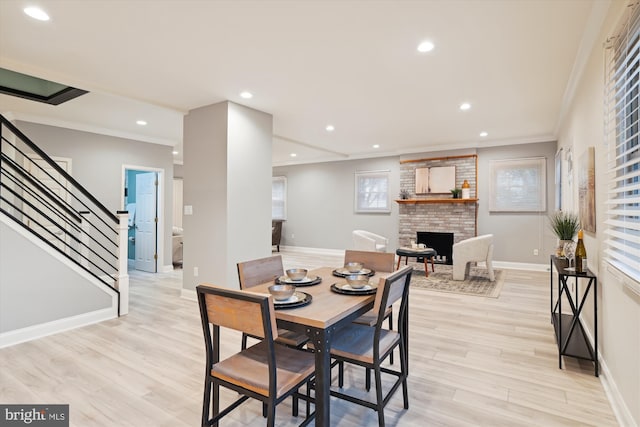 dining area with crown molding, a fireplace, and light wood-type flooring