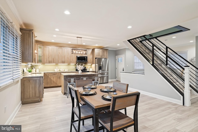 dining space featuring light hardwood / wood-style flooring, crown molding, and sink