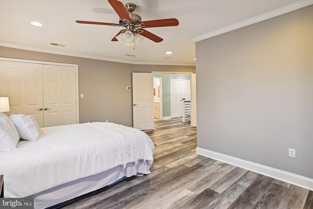 bedroom with hardwood / wood-style floors, ceiling fan, crown molding, and a closet