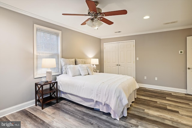 bedroom with a closet, crown molding, ceiling fan, and dark wood-type flooring