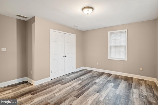 unfurnished bedroom with wood-type flooring and a closet