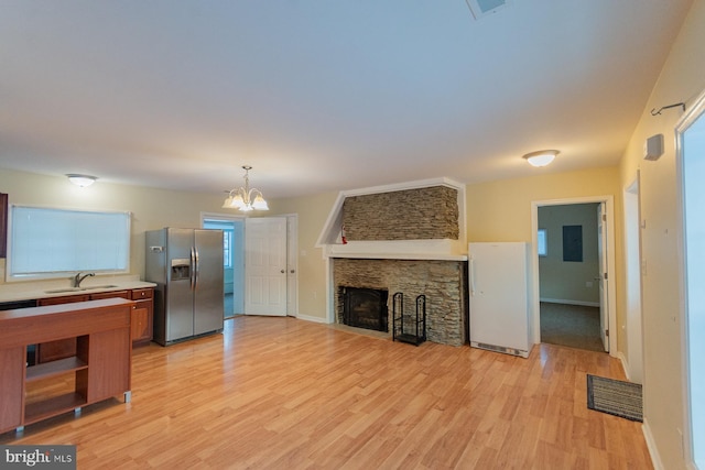 living room featuring sink, a fireplace, a chandelier, and light wood-type flooring