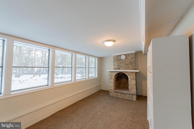 unfurnished living room with carpet floors and a stone fireplace