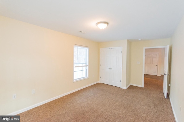 unfurnished bedroom featuring a closet and light carpet