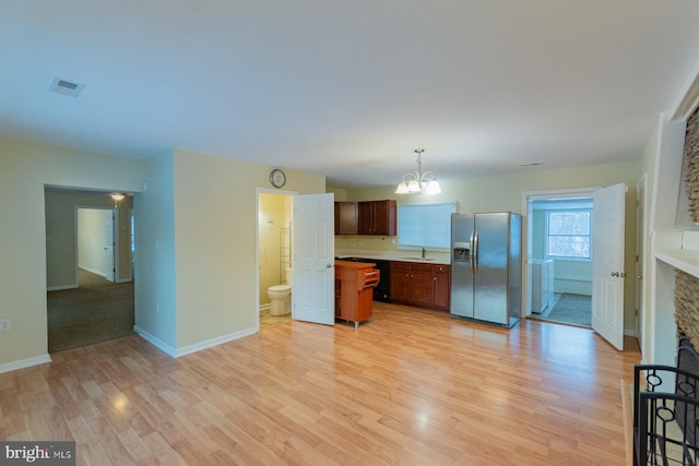 kitchen featuring sink, decorative light fixtures, light hardwood / wood-style flooring, and stainless steel fridge