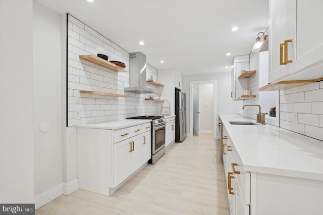 kitchen featuring sink, stainless steel appliances, wall chimney range hood, tasteful backsplash, and white cabinets