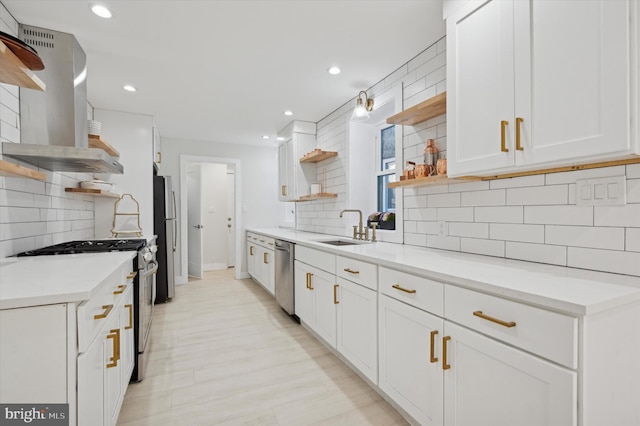 kitchen featuring white cabinetry, sink, wall chimney range hood, decorative backsplash, and appliances with stainless steel finishes