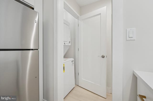 laundry area featuring light wood-type flooring and stacked washer / dryer