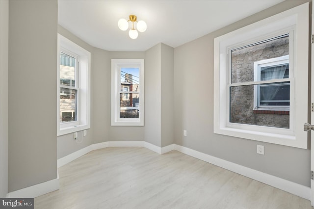 spare room featuring an inviting chandelier and light hardwood / wood-style flooring