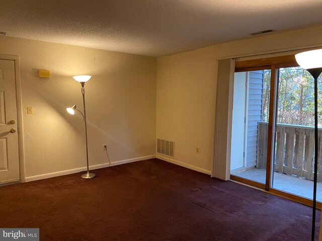 carpeted empty room featuring a textured ceiling