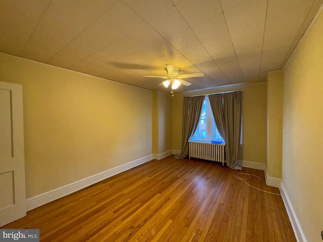 spare room featuring hardwood / wood-style flooring, ceiling fan, and radiator