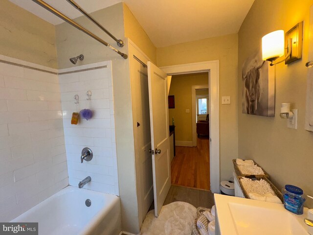 bathroom with hardwood / wood-style floors, vanity, and tiled shower / bath