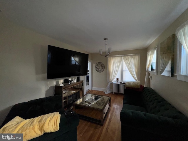 living room with radiator heating unit, dark wood-type flooring, and a notable chandelier