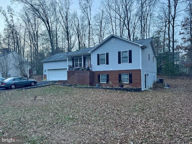 view of front of property with central air condition unit, a porch, and a garage