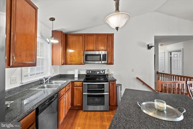 kitchen with sink, lofted ceiling, stainless steel appliances, and hanging light fixtures