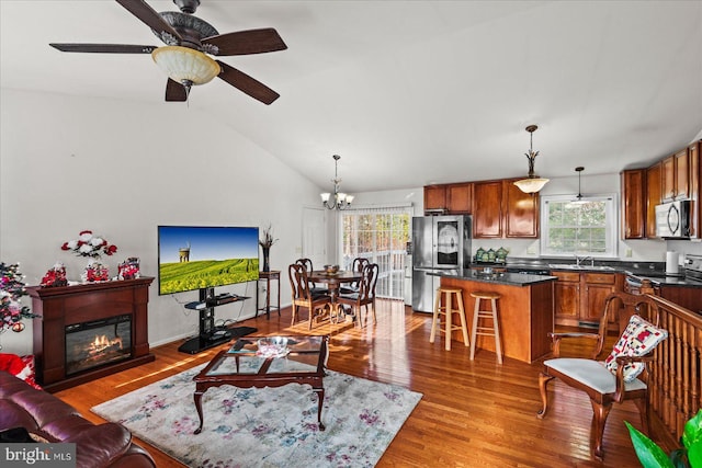 living room with wood-type flooring, ceiling fan with notable chandelier, lofted ceiling, and sink