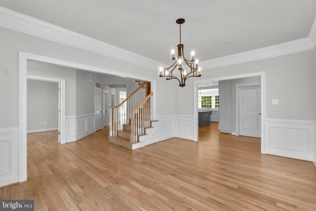 empty room with a chandelier, crown molding, and light hardwood / wood-style floors