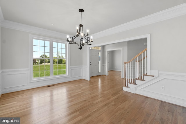 unfurnished dining area featuring light hardwood / wood-style floors, ornamental molding, and a chandelier