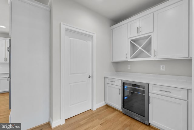 bar with white cabinetry, wine cooler, and light hardwood / wood-style floors