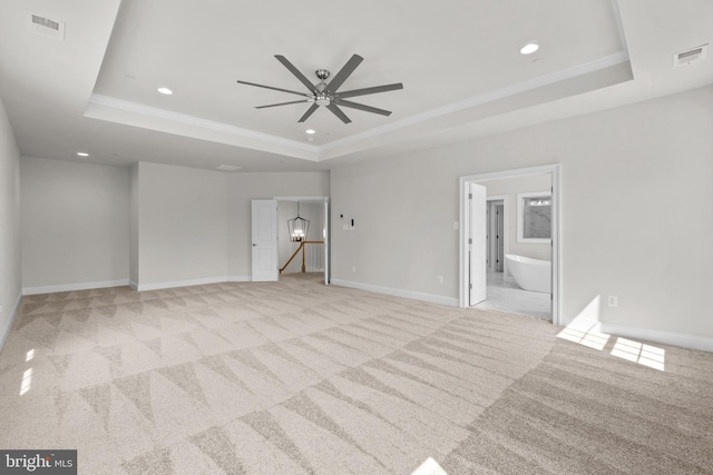 spare room featuring a tray ceiling, ceiling fan, and light colored carpet