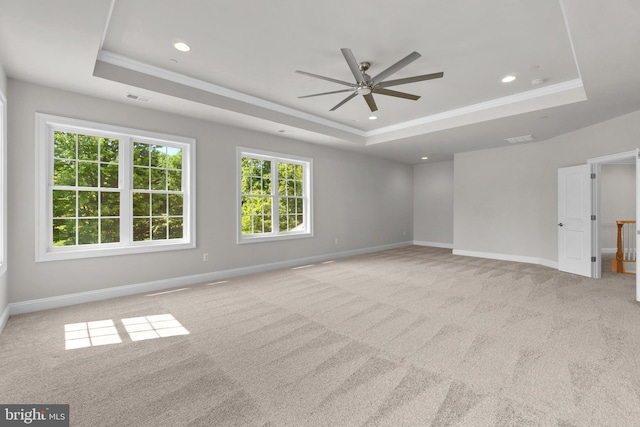 spare room with a tray ceiling, ceiling fan, crown molding, and light colored carpet