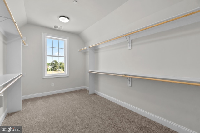 spacious closet with light colored carpet and lofted ceiling