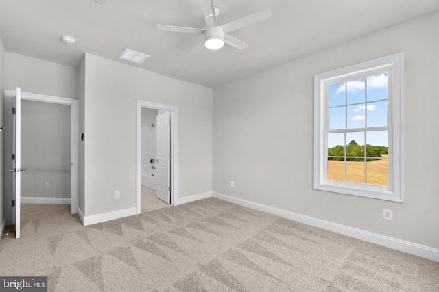 unfurnished bedroom featuring light colored carpet, ensuite bath, and ceiling fan