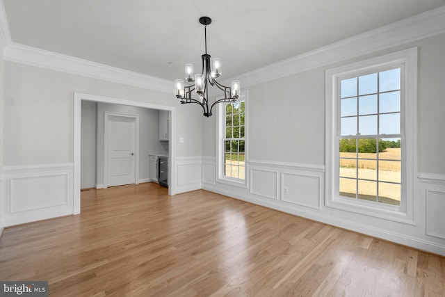 unfurnished dining area featuring light hardwood / wood-style flooring, ornamental molding, and a notable chandelier