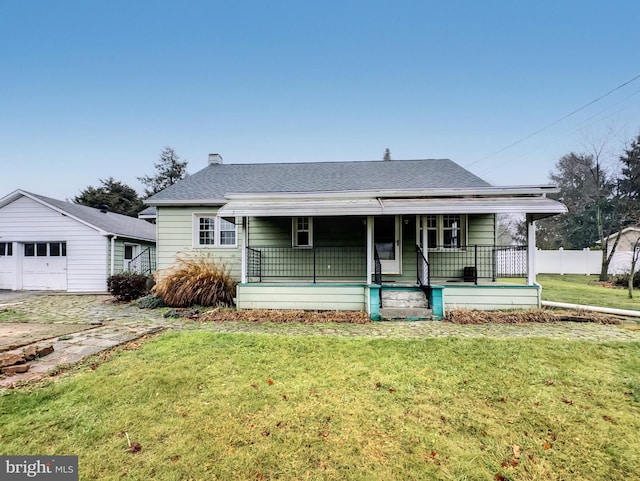 view of front of house with an outdoor structure, covered porch, a front yard, and a garage