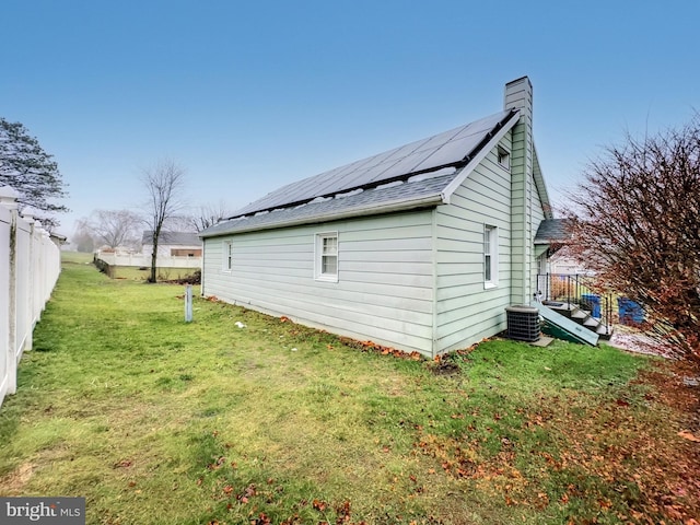 view of side of property with solar panels, central air condition unit, and a lawn