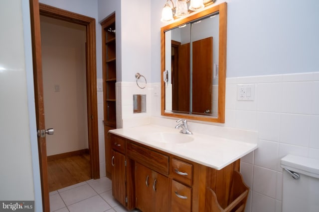 bathroom with tile patterned flooring, vanity, toilet, and tile walls