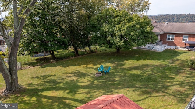 view of yard featuring a trampoline and an outdoor fire pit