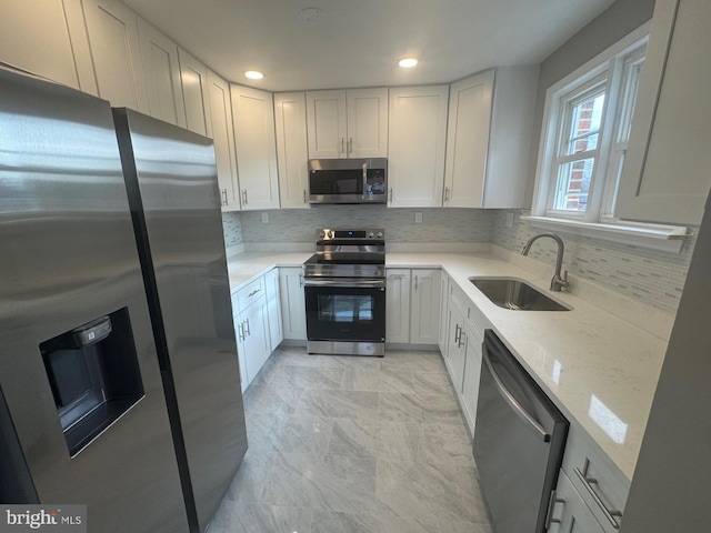 kitchen with light stone countertops, sink, tasteful backsplash, white cabinets, and appliances with stainless steel finishes