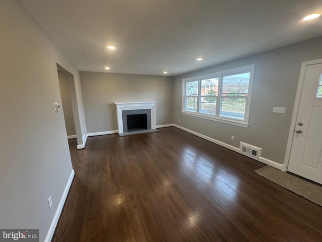 unfurnished living room featuring dark hardwood / wood-style flooring and a brick fireplace