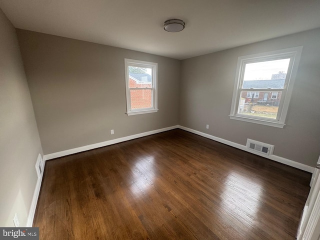 empty room with dark wood-type flooring and a healthy amount of sunlight