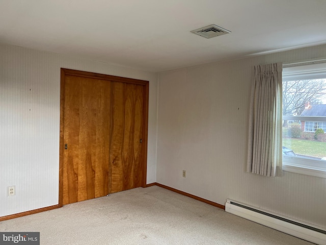 unfurnished bedroom with baseboard heating, a closet, and carpet