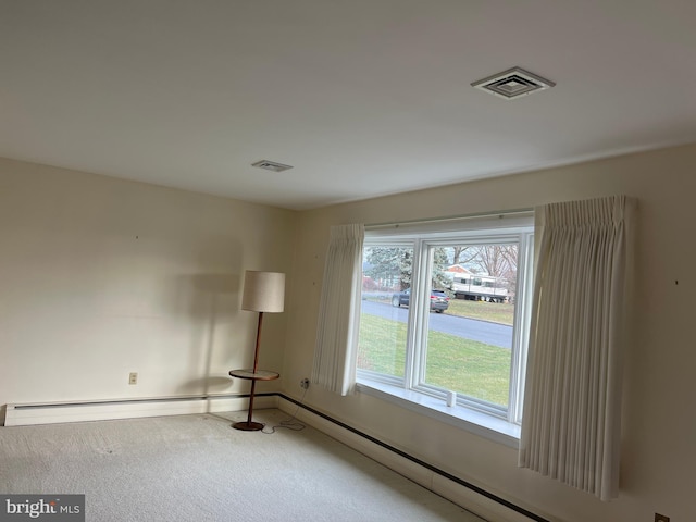 carpeted spare room with a baseboard heating unit