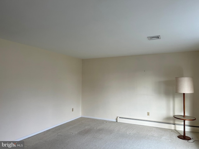 carpeted spare room featuring a baseboard heating unit