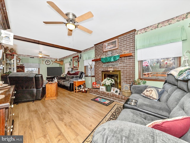 living room with a fireplace, beam ceiling, light hardwood / wood-style floors, and ceiling fan