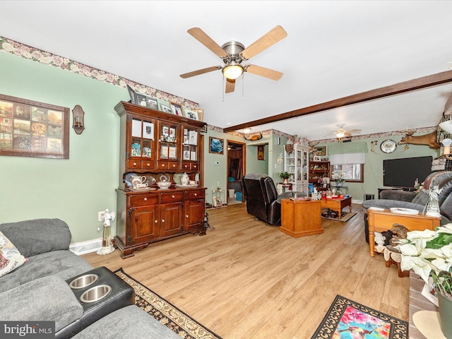 living room with ceiling fan, beamed ceiling, and light hardwood / wood-style floors