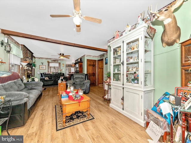 living room featuring beamed ceiling, ceiling fan, light hardwood / wood-style floors, and a brick fireplace